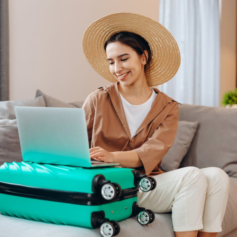woman-booking-trip-on-computer-with-suitcase