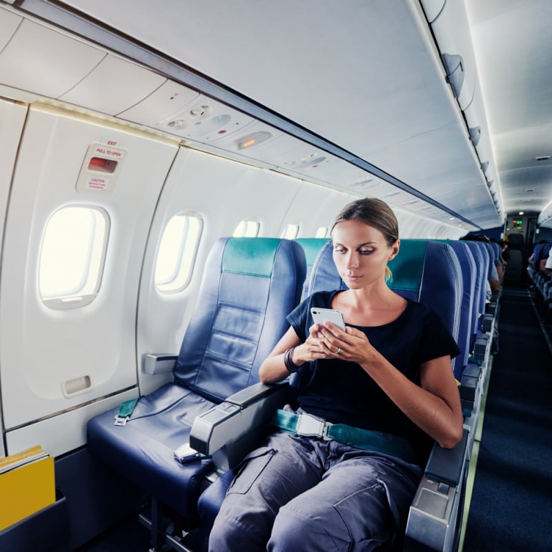 Woman using cell phone on airplane
