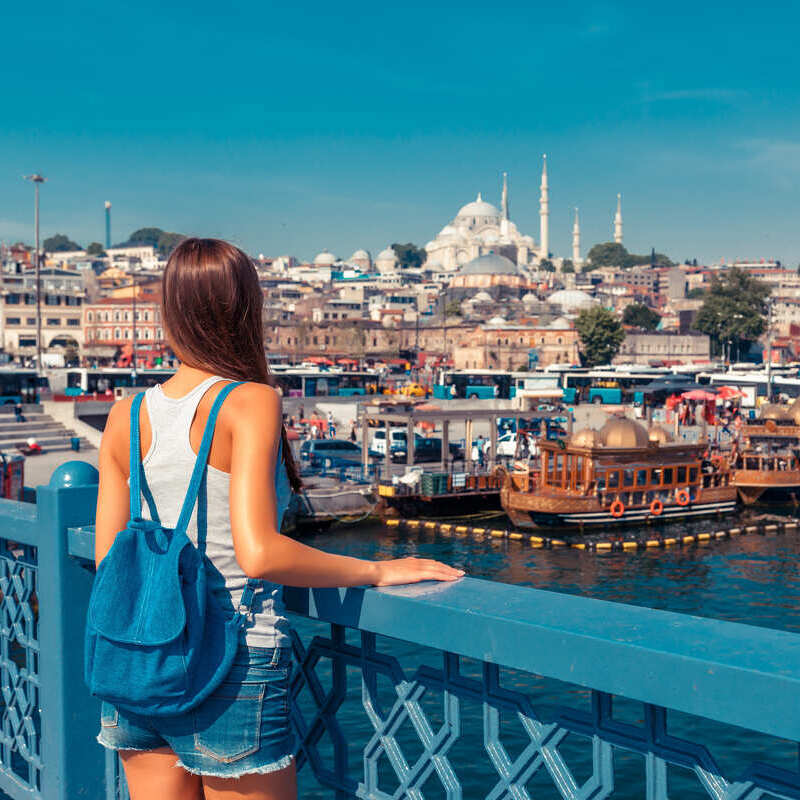 Young tourist woman photographed with her backpack as she stands on the Galata bridge looking at the historic peninsula of Istanbul, Turkyie, Turkey, Eurasia, Middle East, Eastern Europe