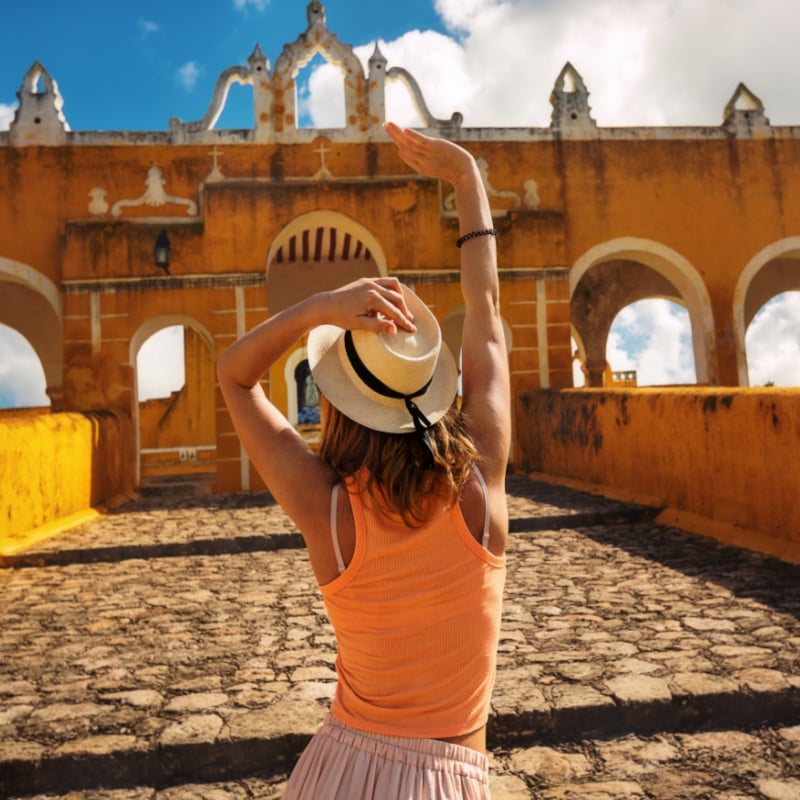 Tourist girl in a sombrero in the yellow Mexican city of Izamal, Mexico