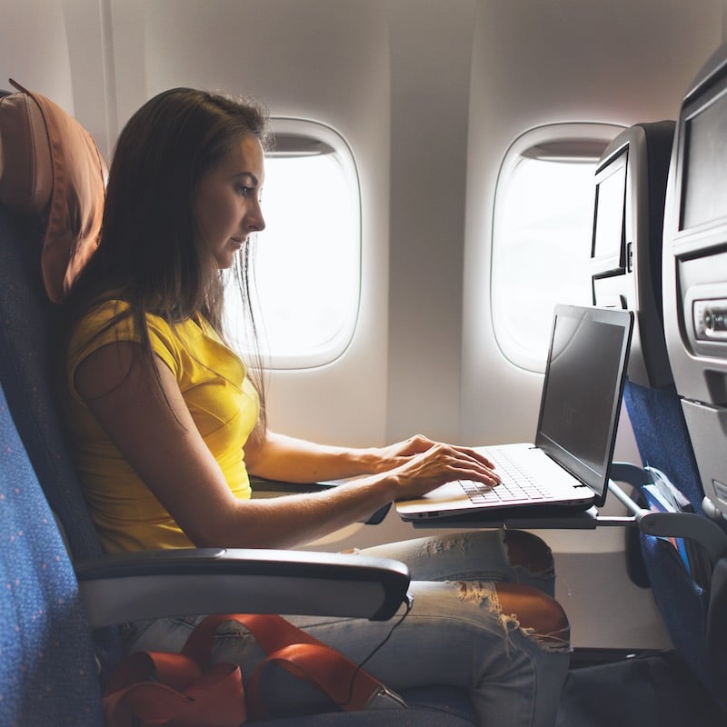 Woman using computer in airplane cabin