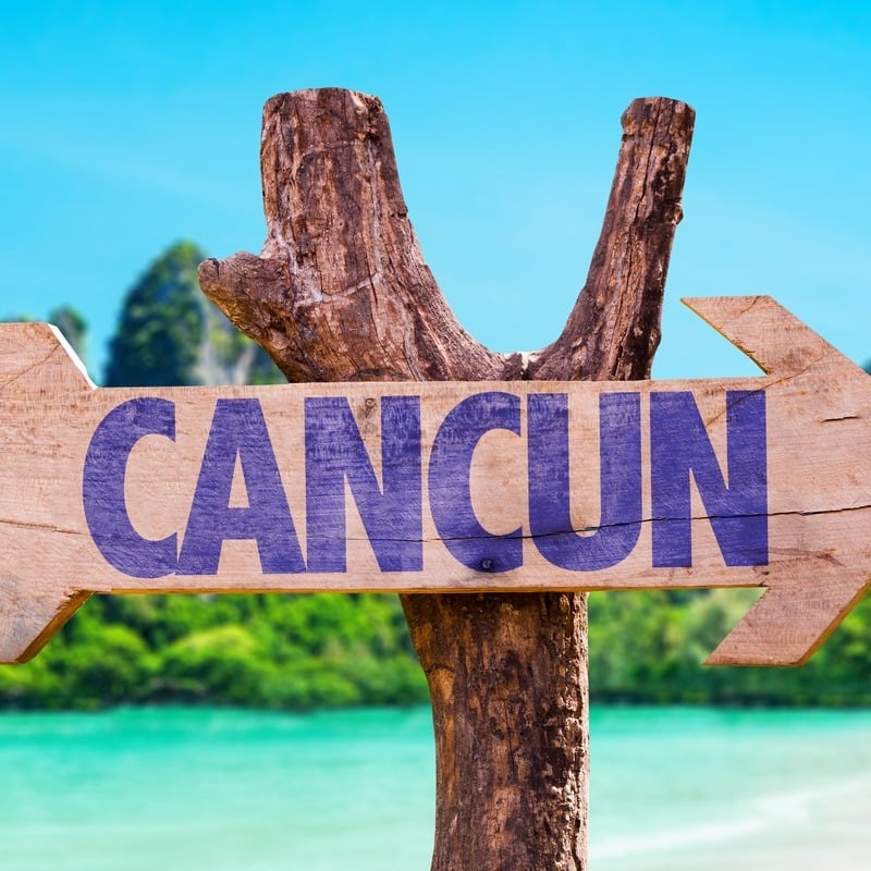 Sign pointing towards Cancun pictured in a tropical location along the Caribbean Sea, Riviera Maya, Mexico