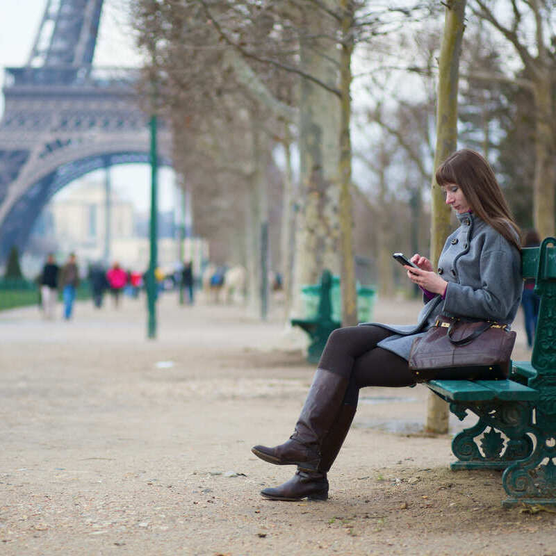 Young woman looking at her phone at near Eiffel Tower, Paris, France