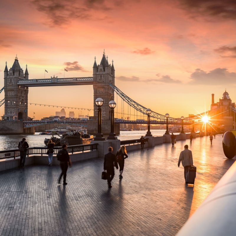 People pass by Tower Bridge as the sun rises. 