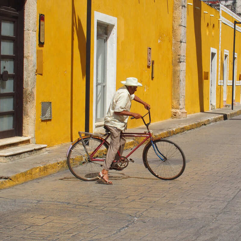 Mexican man riding his bicycle through the yellow streets of Colonial Izamal, in the Yucatan peninsula of Mexico, Latin America