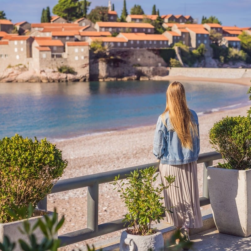 Tourist woman observing the island Sveti Stefan Resort in Montenegro, in the Adriatic section of the Mediterranean sea, South Eastern Europe, Balkan Peninsula