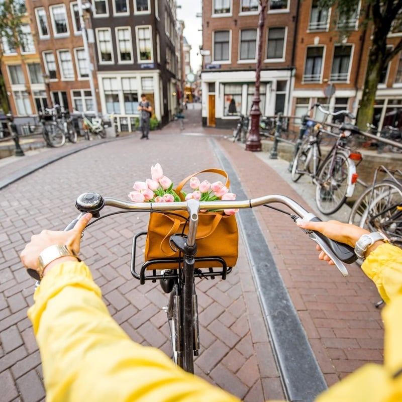 Cyclist Point Of View Picture As They Ride Through A Bridge Spanning A Canal In Old Town Amsterdam, The Capital Of The Netherlands, In The Holland Region, Europe