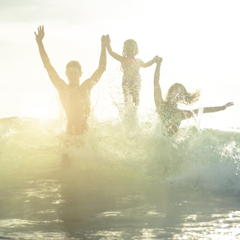 happy family splashing in the waves on the beach in mexico